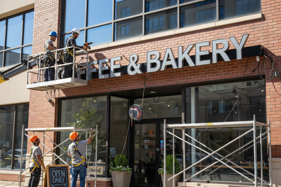 Team installing COFFEE & BAKERY sign on a storefront